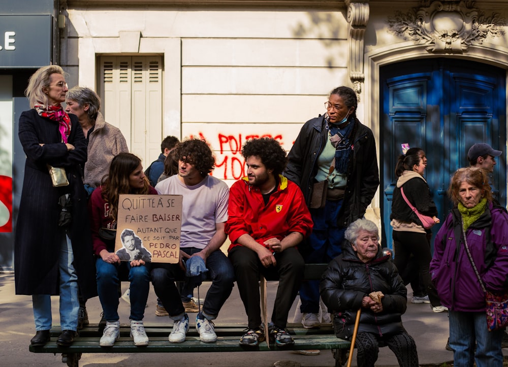 a group of people sitting on a bench in front of a building