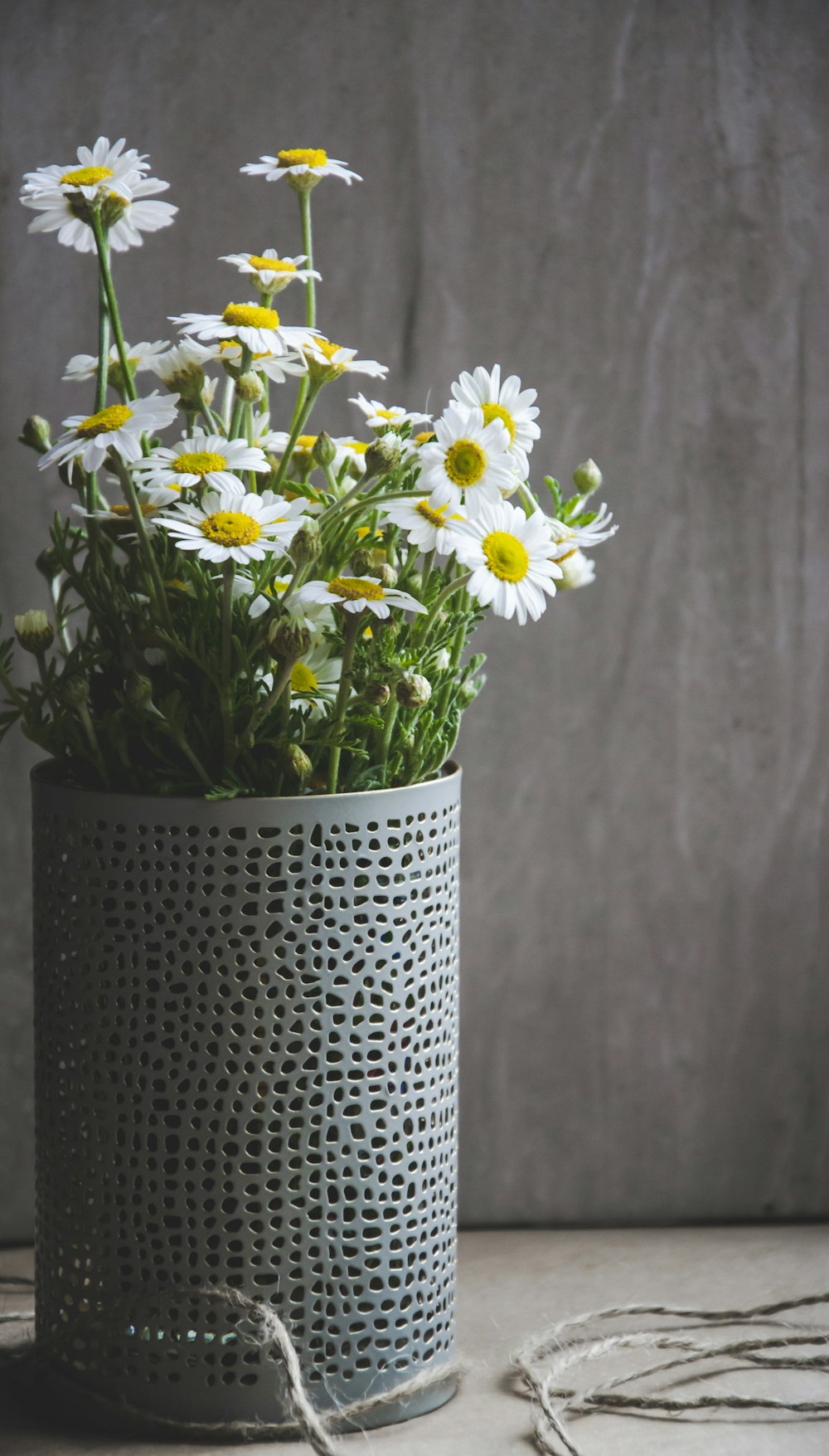 a vase filled with lots of white and yellow flowers