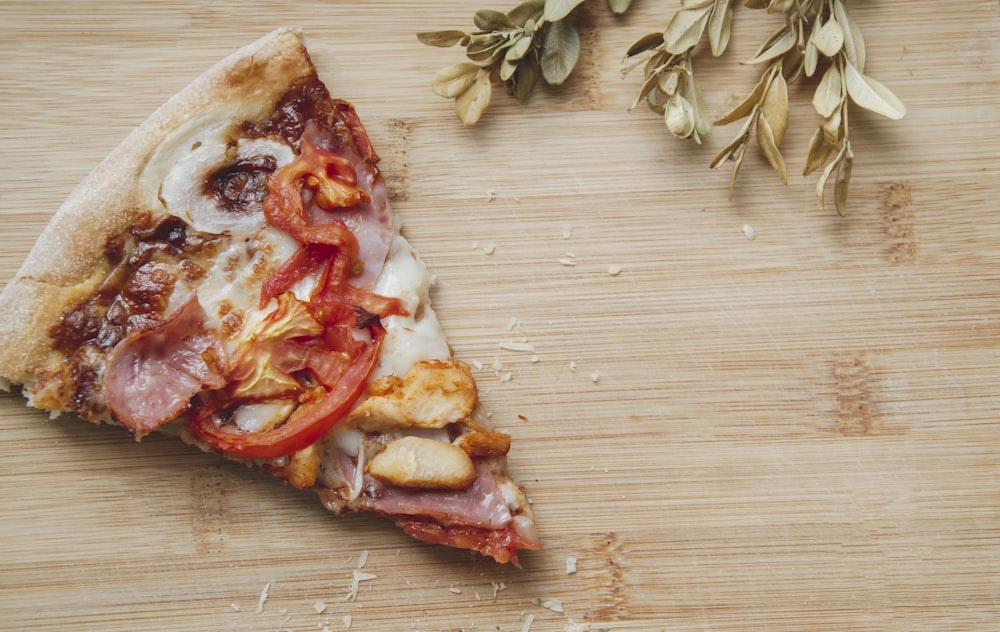 ein Stück Pizza, das auf einem hölzernen Schneidebrett sitzt