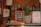 A small chalkboard sign offers a 15% discount for NHS workers and students. The sign is placed on a counter beside a potted plant with long, pointed green leaves. A bag of 'South Coast Coffee' is to the right of the plant. The scene is set in a cozy coffee shop environment with stacks of items in the background.