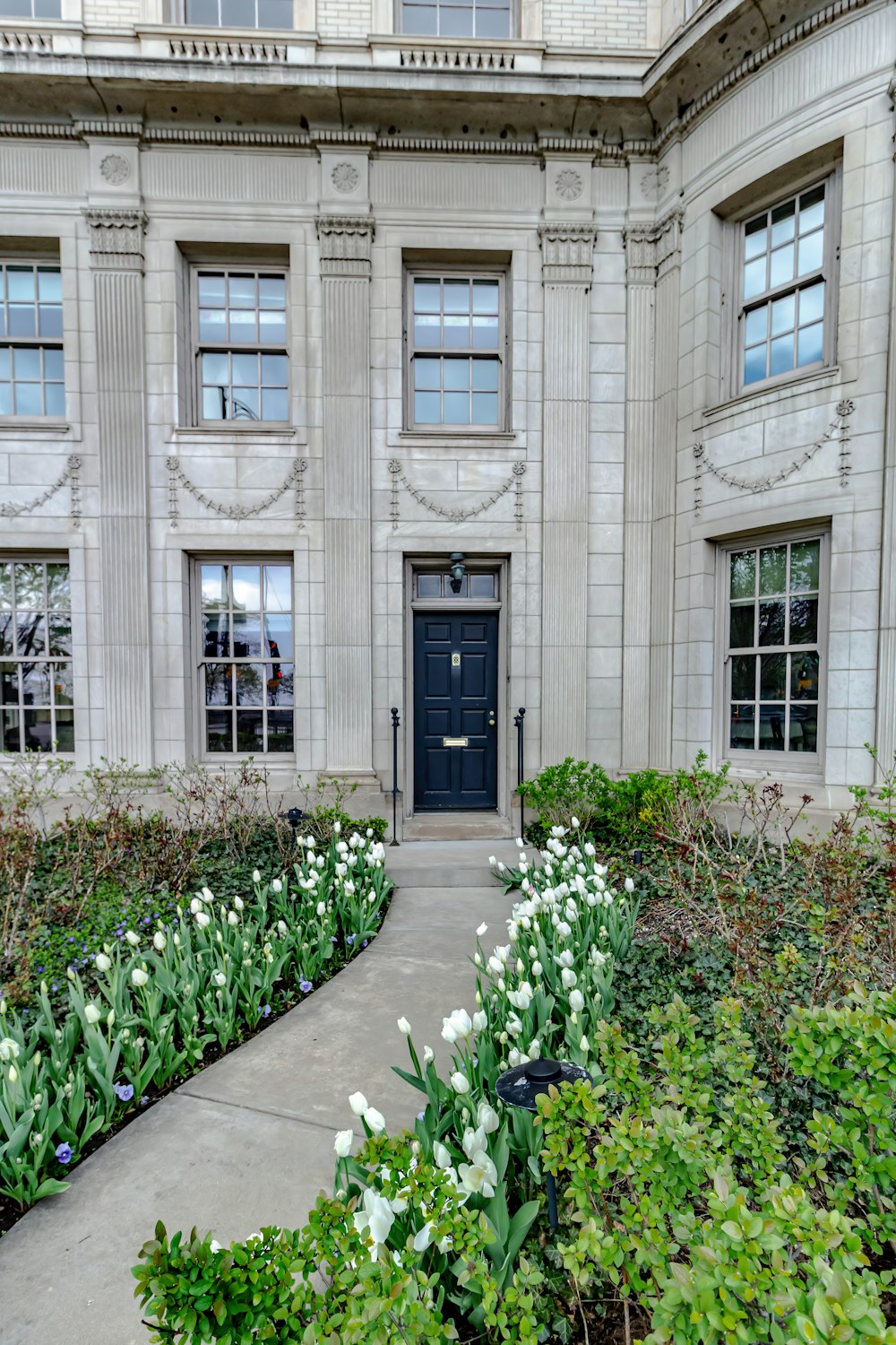 a large building with a black door and a bunch of flowers