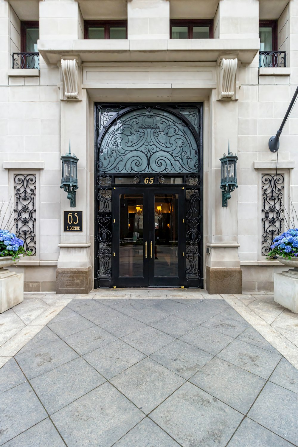 the entrance to a building with blue flowers in front of it