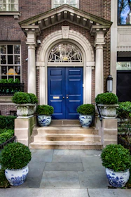 Elegant entrance porch with a blue-tinted glass roof matching the brand colors