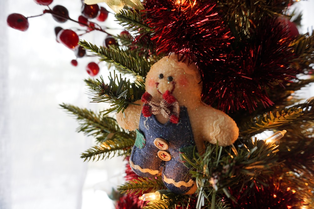a teddy bear ornament hanging from a christmas tree