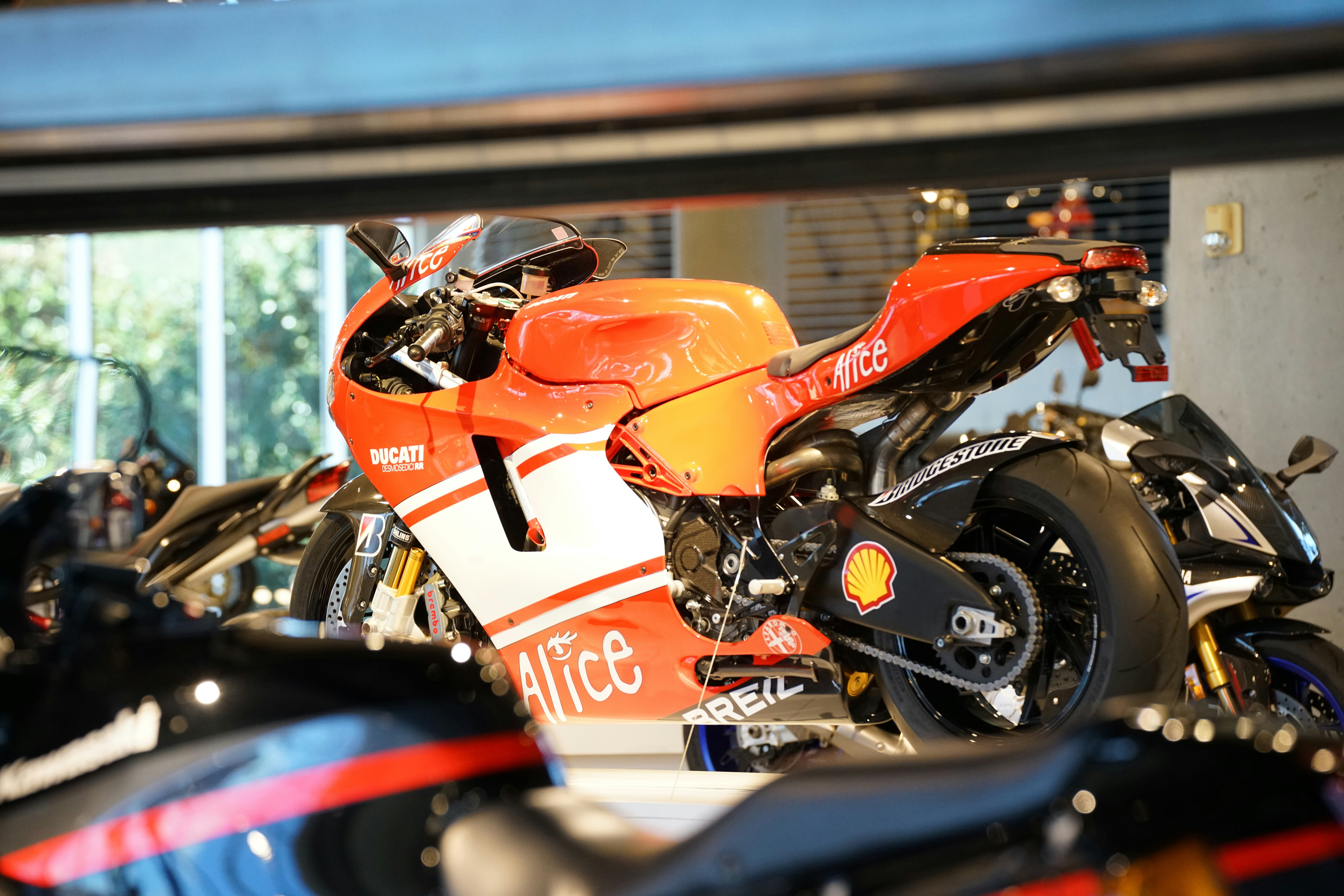 an orange motorcycle parked in a garage next to other motorcycles