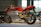 A red and silver sports motorcycle is displayed in a well-lit showroom. The sleek design highlights its aerodynamic features and modern engineering. The motorcycle is elevated on a platform, allowing a clear view of its intricate details, such as the wheel rims and the suspension system.