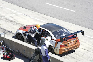 Hugo coaching a young driver, pointing out key techniques next to a race car in the pit lane