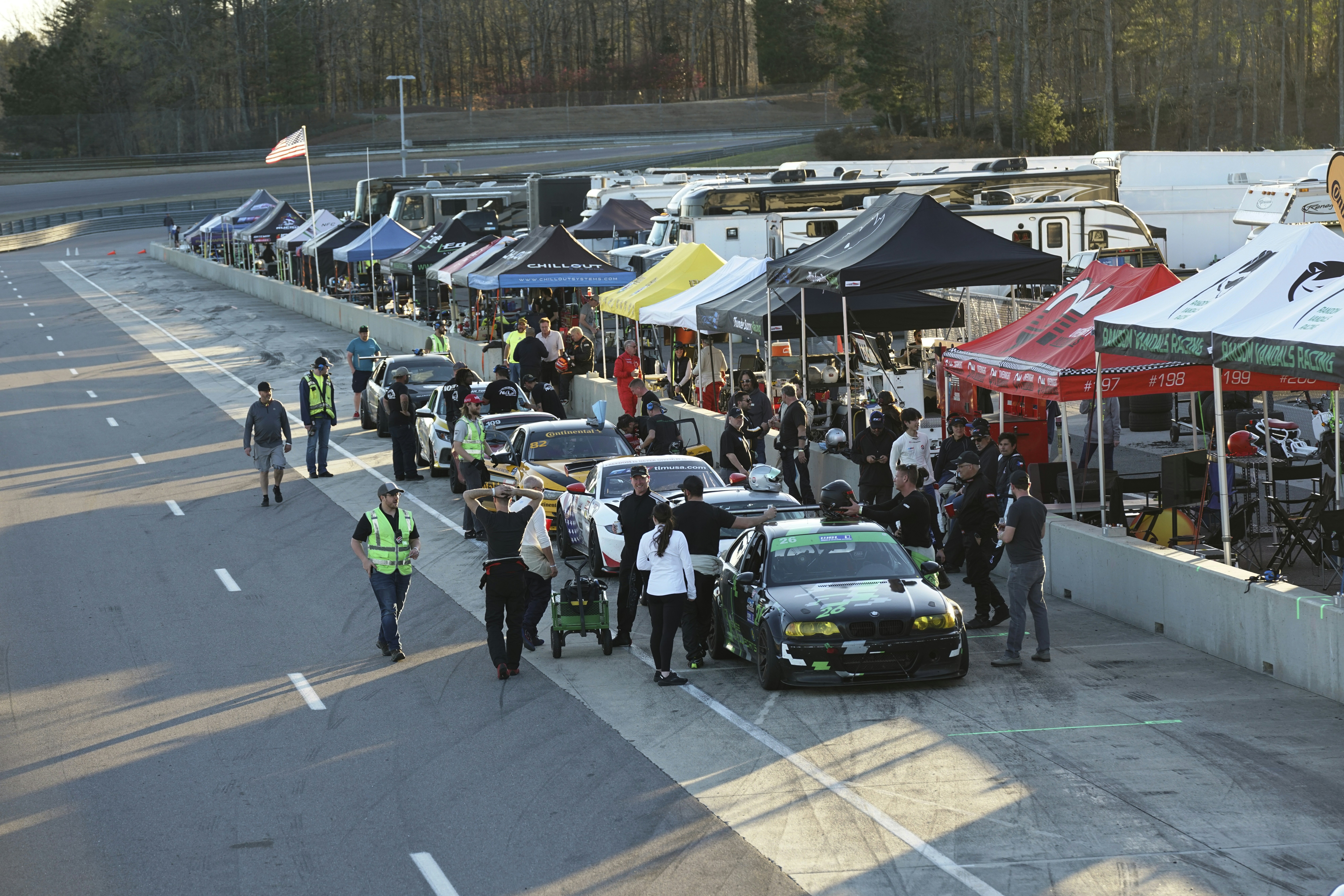 a group of people standing next to a line of parked cars