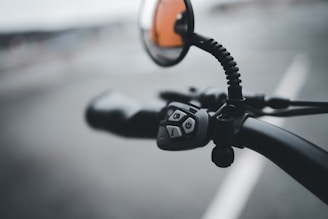 Close-up of a sleek lane switch can holder mounted on a motorcycle handlebar with a blurred road background.