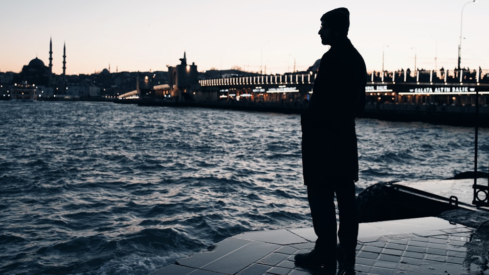 a man standing next to a body of water