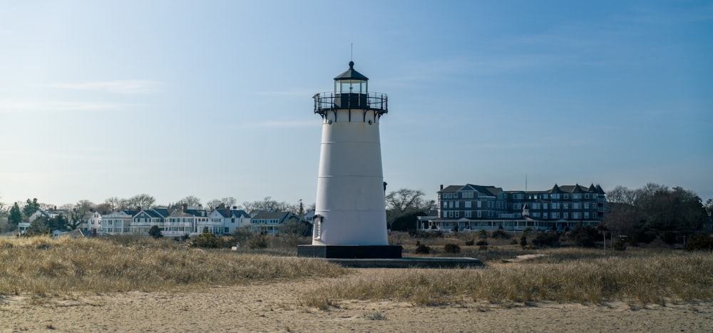 a lighthouse on a beach with houses in the background