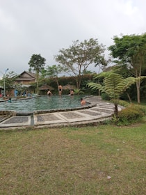 Guests relaxing by a serene outdoor pool surrounded by lush greenery.