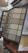 An assortment of carpet samples displayed on a standing rack, featuring various textures and colors including beige, blue, and gray. The setup is indoors, likely in a showroom or retail store, with a focus on home decor options.