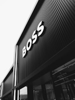A black and white photograph of a building with large signage displaying the word 'BOSS' in bold letters. The architecture features vertical lines that create a modern and sleek appearance.