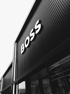 A black and white photograph of a building with large signage displaying the word 'BOSS' in bold letters. The architecture features vertical lines that create a modern and sleek appearance.