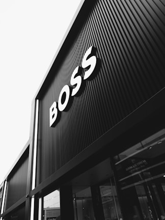 A black and white photograph of a building with large signage displaying the word 'BOSS' in bold letters. The architecture features vertical lines that create a modern and sleek appearance.