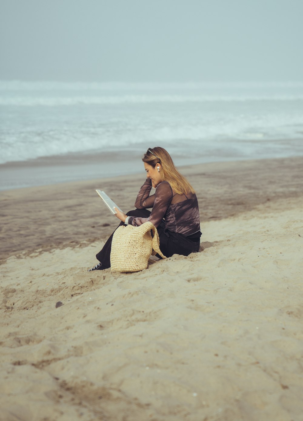 a woman is sitting on the beach reading a book