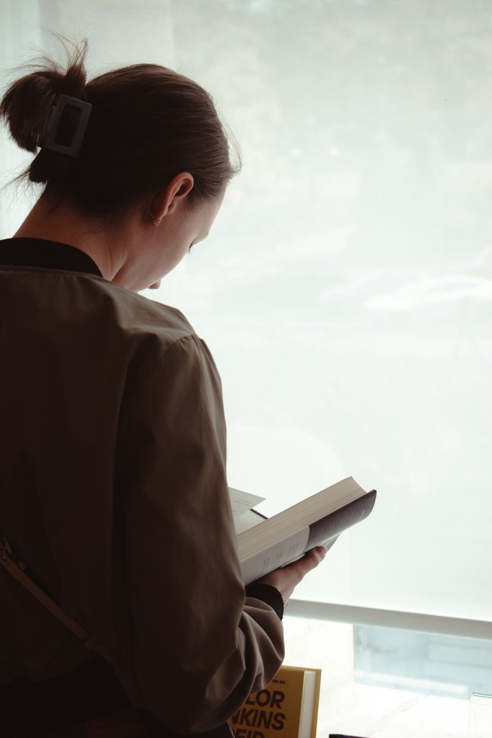 a woman reading a book in front of a window