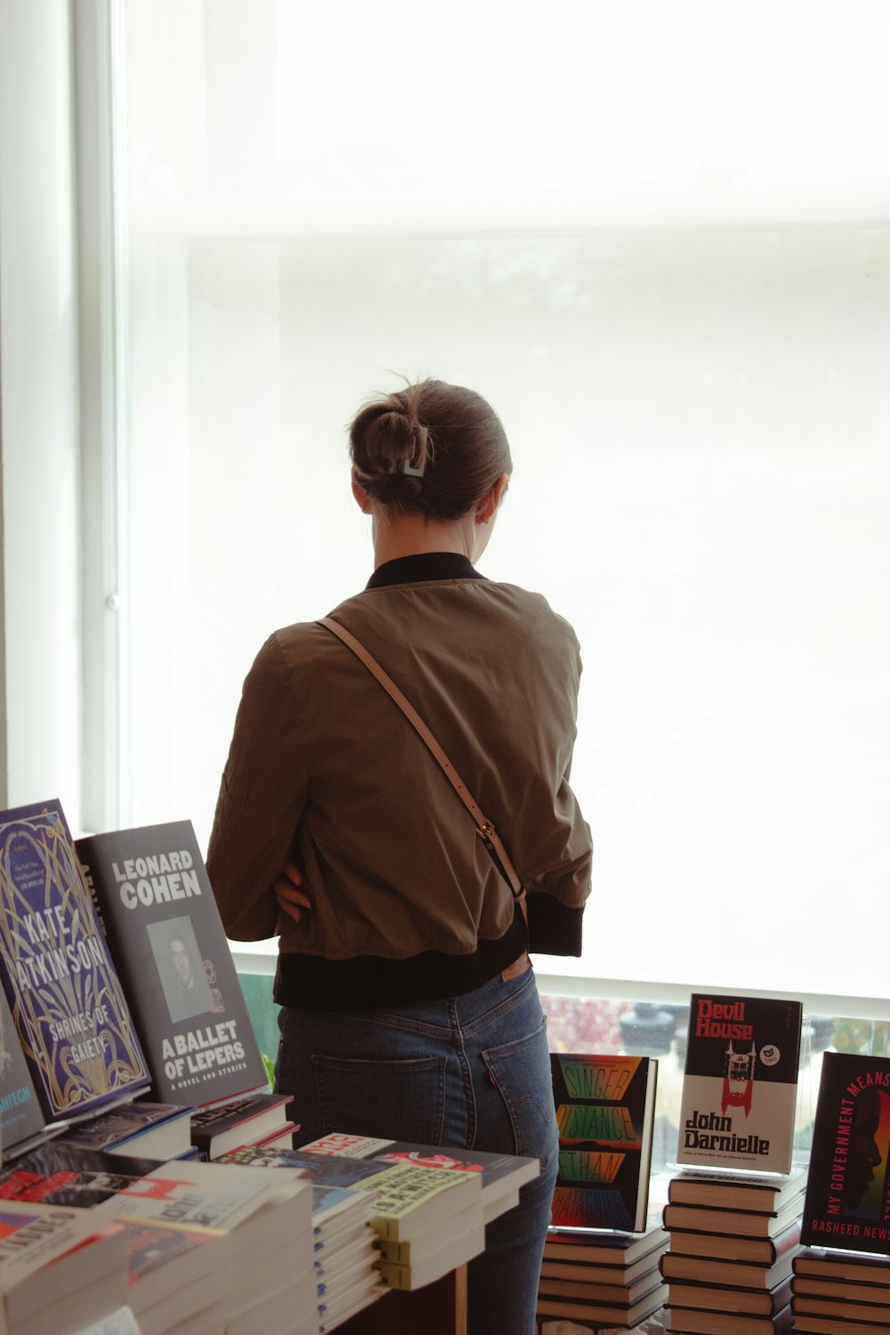 a woman standing in front of a table filled with books