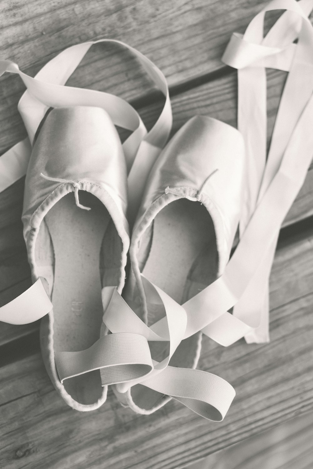 une paire de chaussures de ballet posée sur un plancher en bois