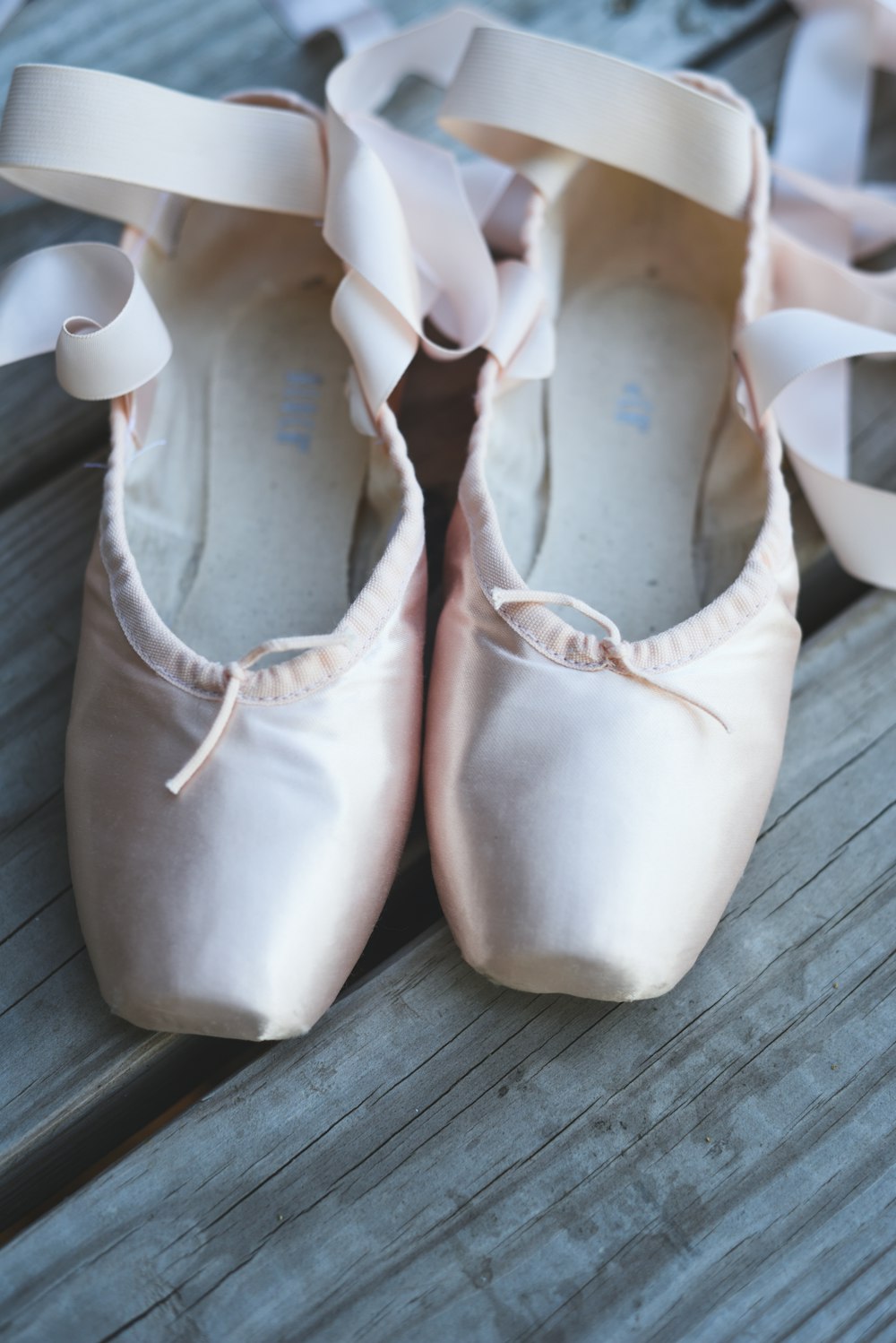 a pair of pink ballet shoes sitting on top of a wooden floor