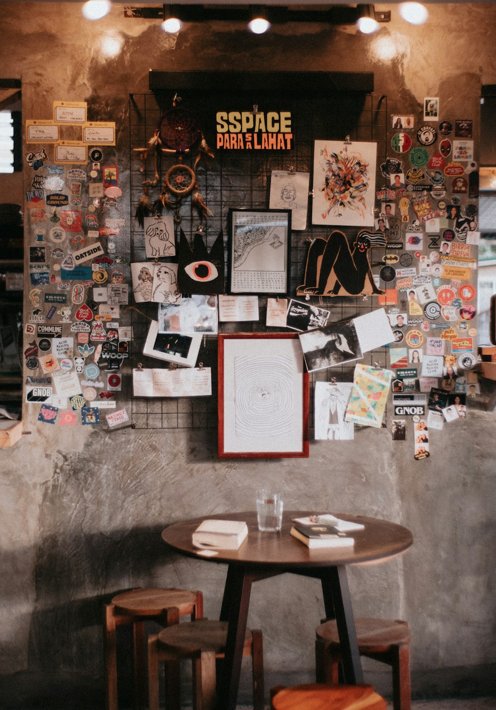 a table with two stools in front of a wall covered with pictures