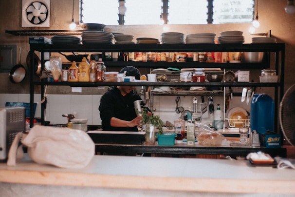 Cozy home kitchen scene with a person preparing a meal and paperwork neatly arranged nearby.