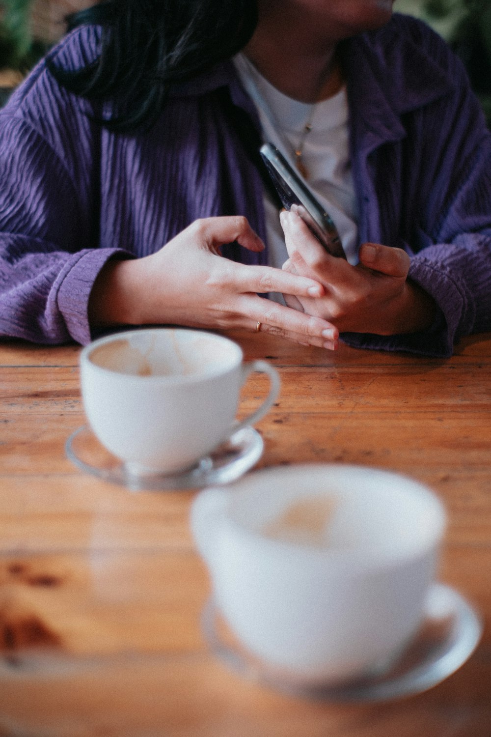 a woman sitting at a table using a cell phone