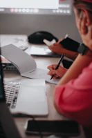 Students collaborating around a table filled with notebooks and pens.