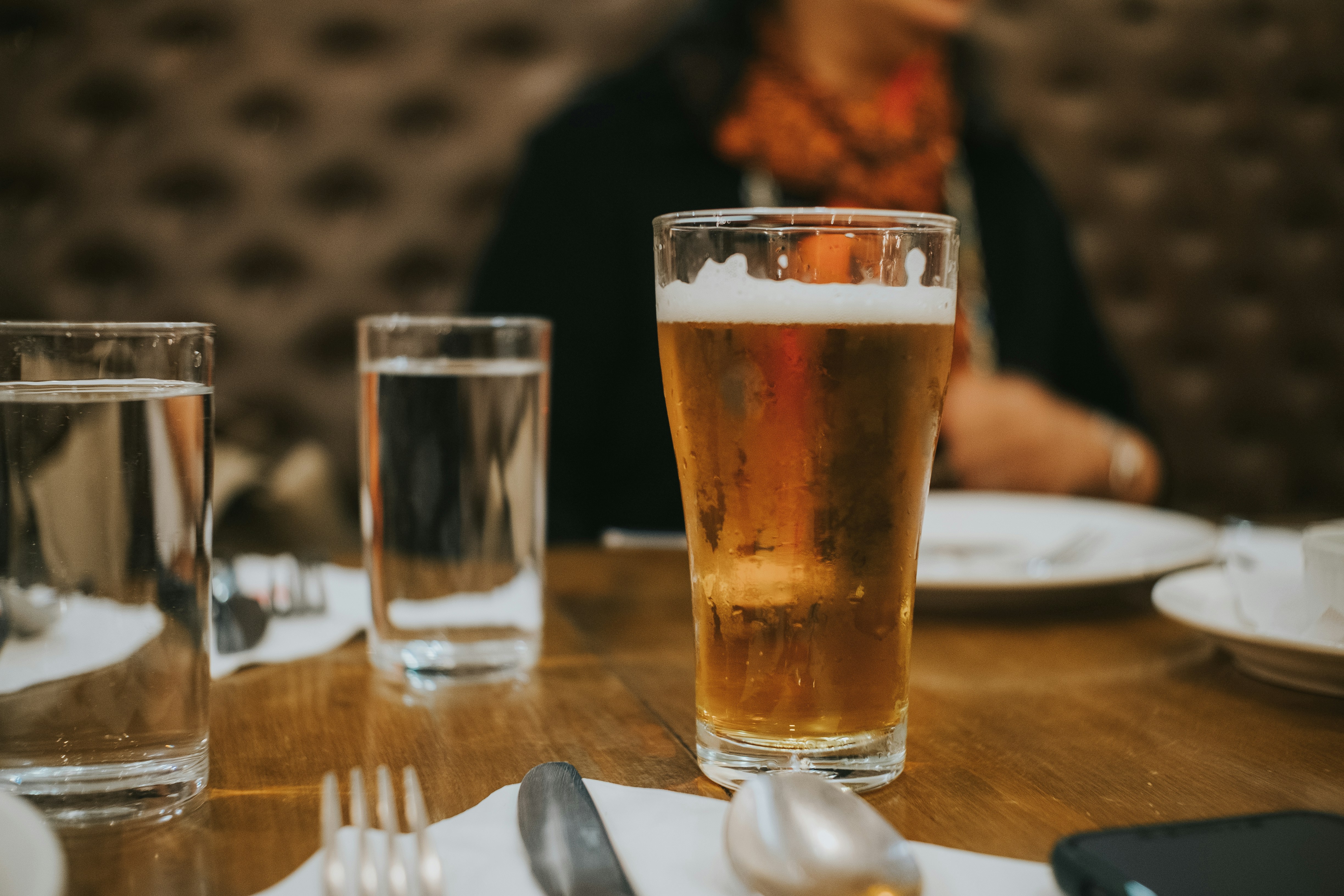 a woman sitting at a table with a glass of beer