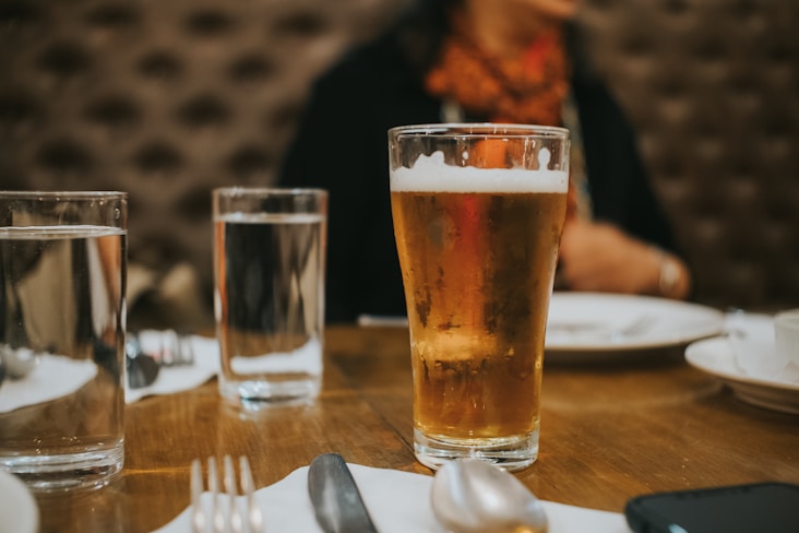 a woman sitting at a table with a glass of beer
