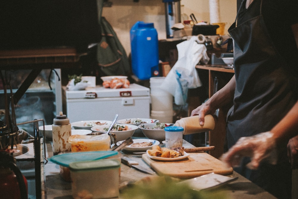 uma pessoa em uma cozinha preparando comida em uma tábua de corte