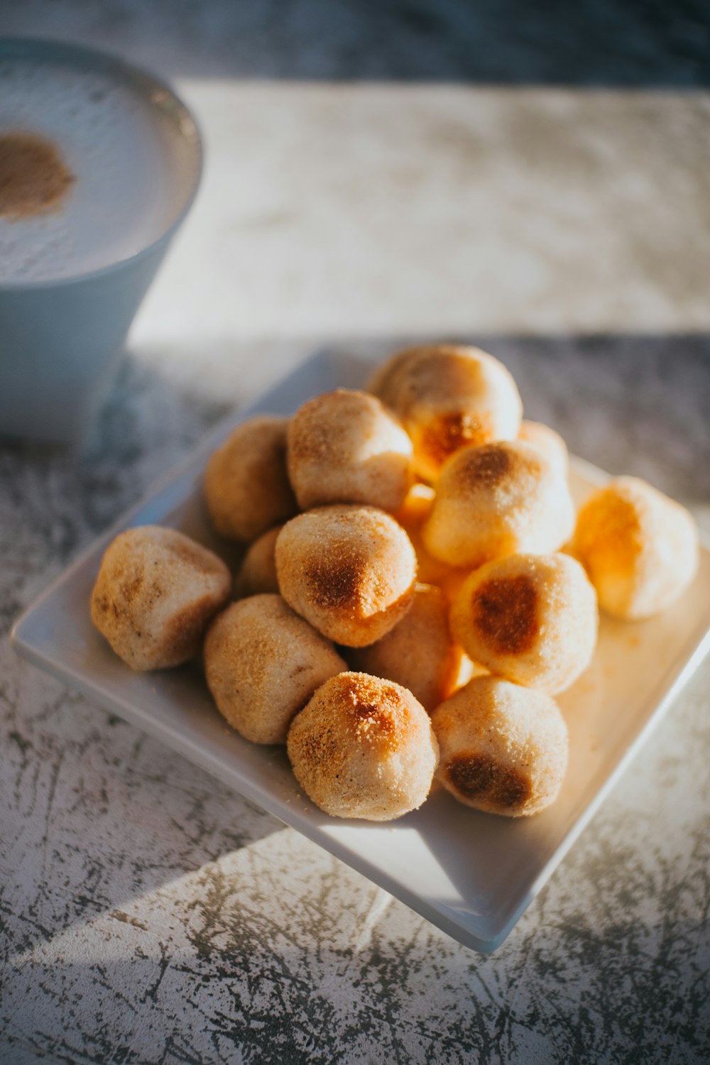 un plato blanco cubierto con donas junto a una taza de café