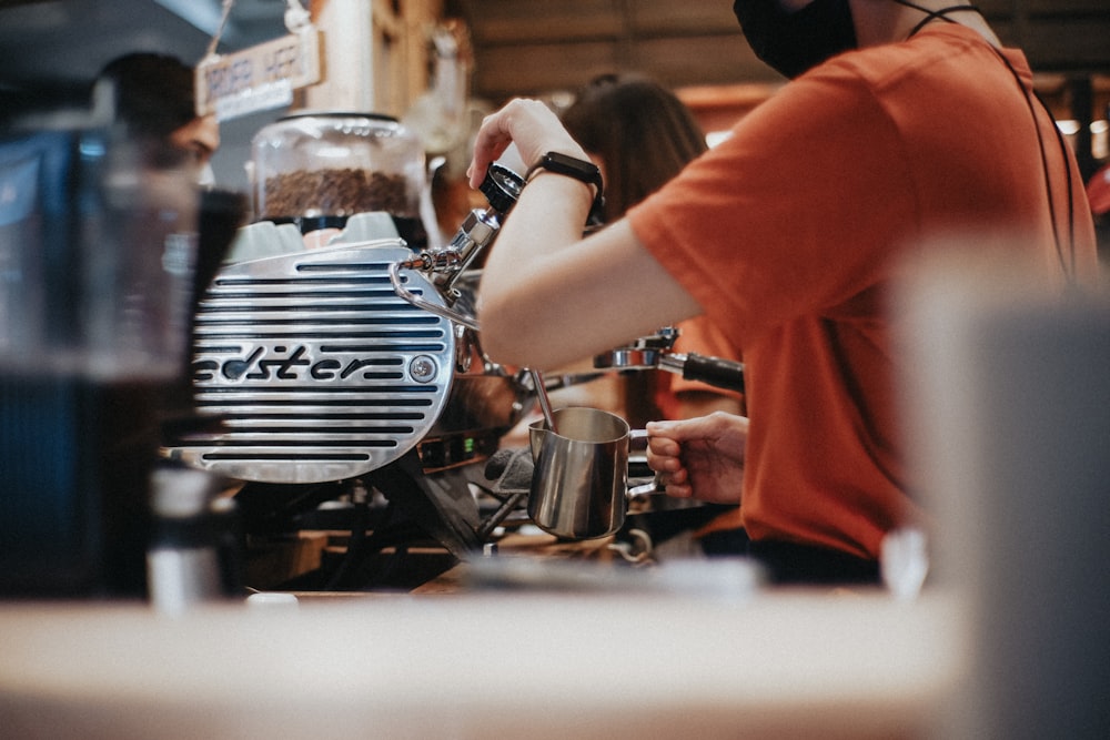 a person in an orange shirt is working on a coffee machine