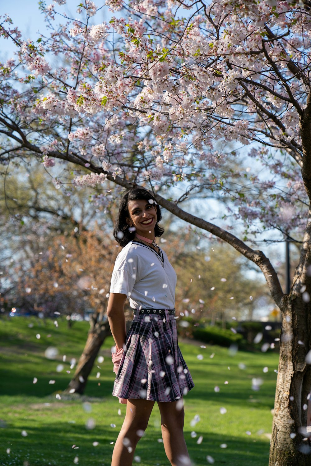 a woman standing in front of a tree in a park