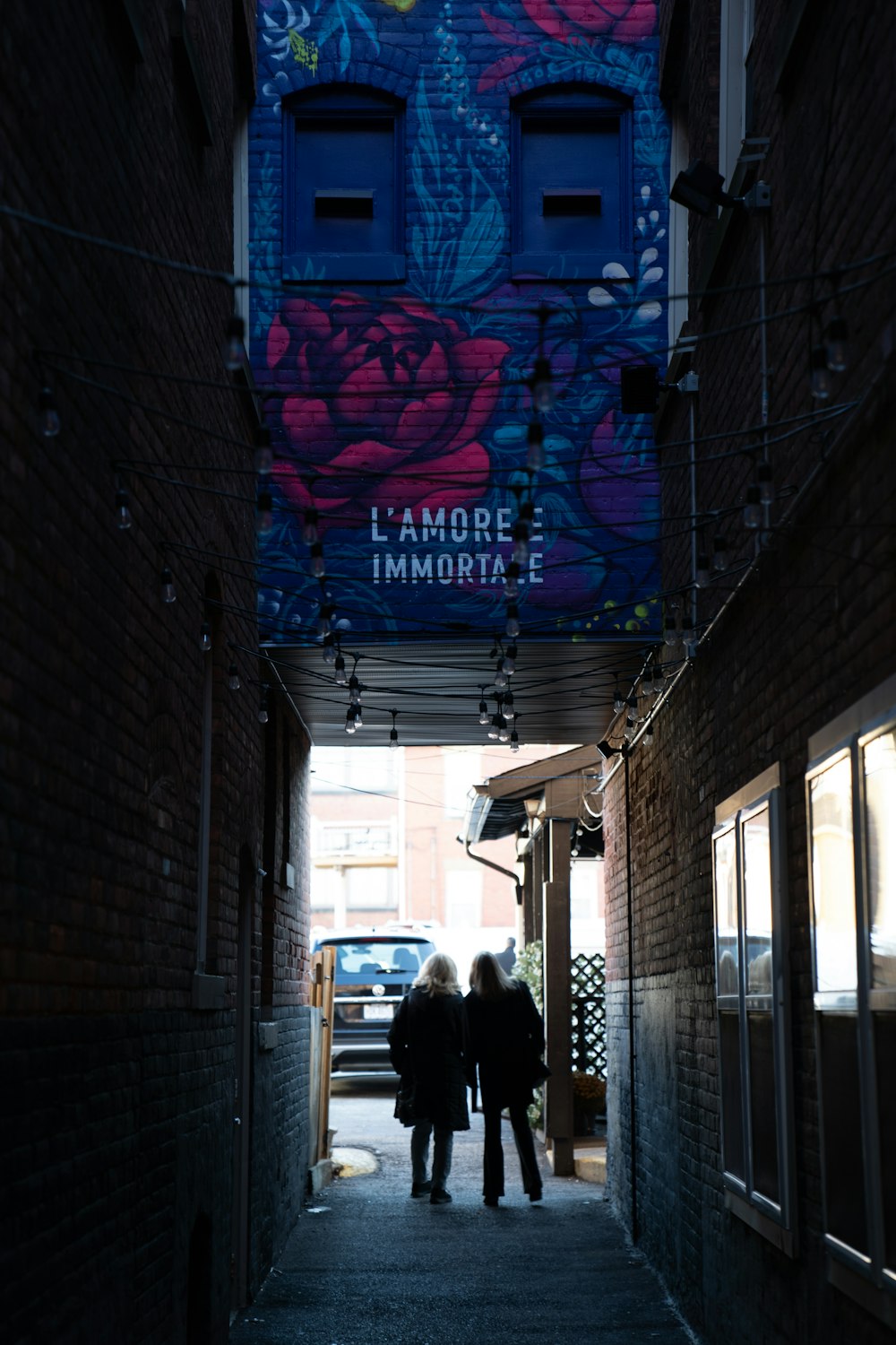 two people walking down a narrow alley way