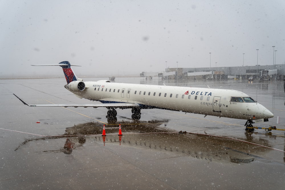 a delta airplane is parked on a wet runway
