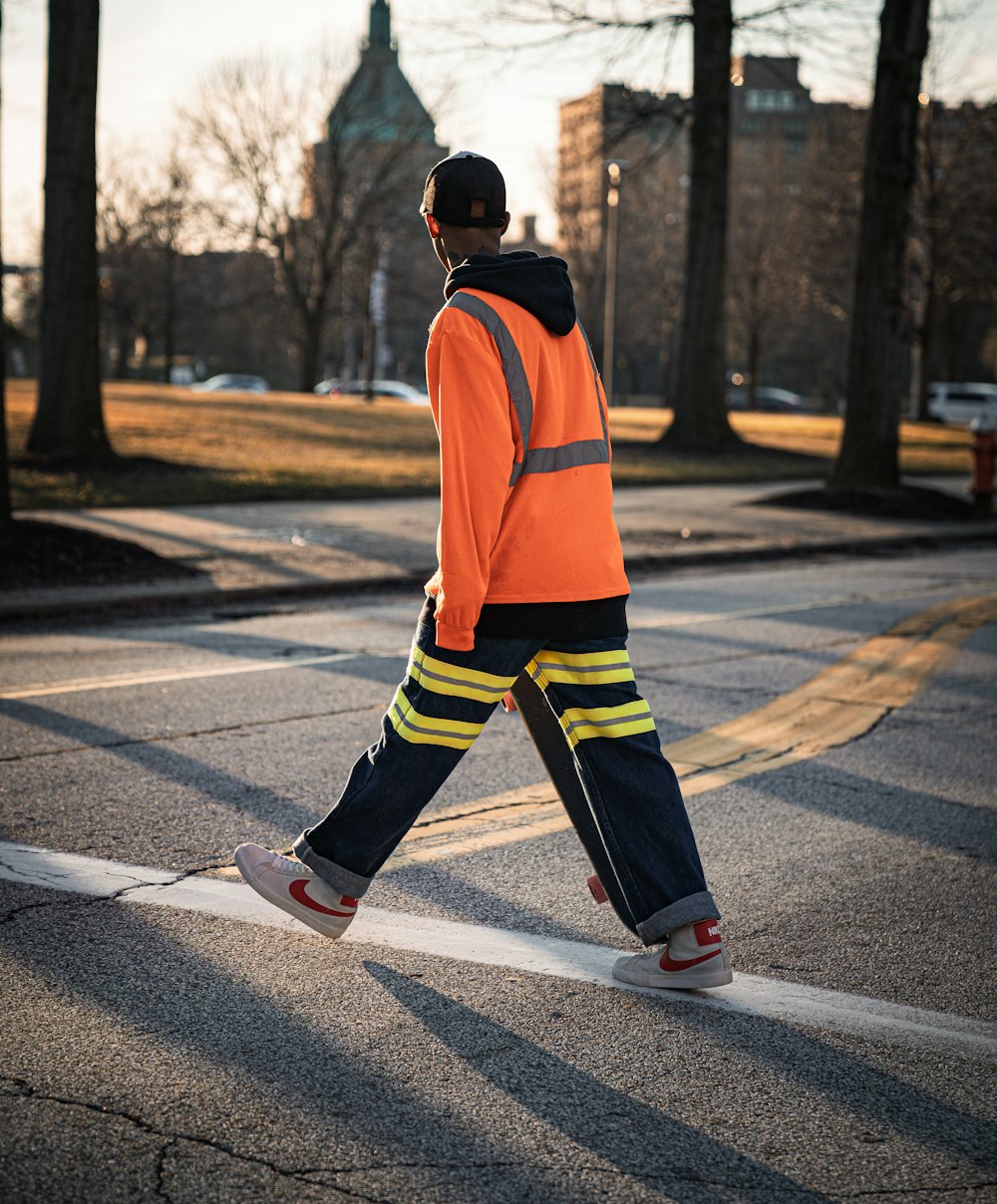 a man in an orange safety vest crossing a street