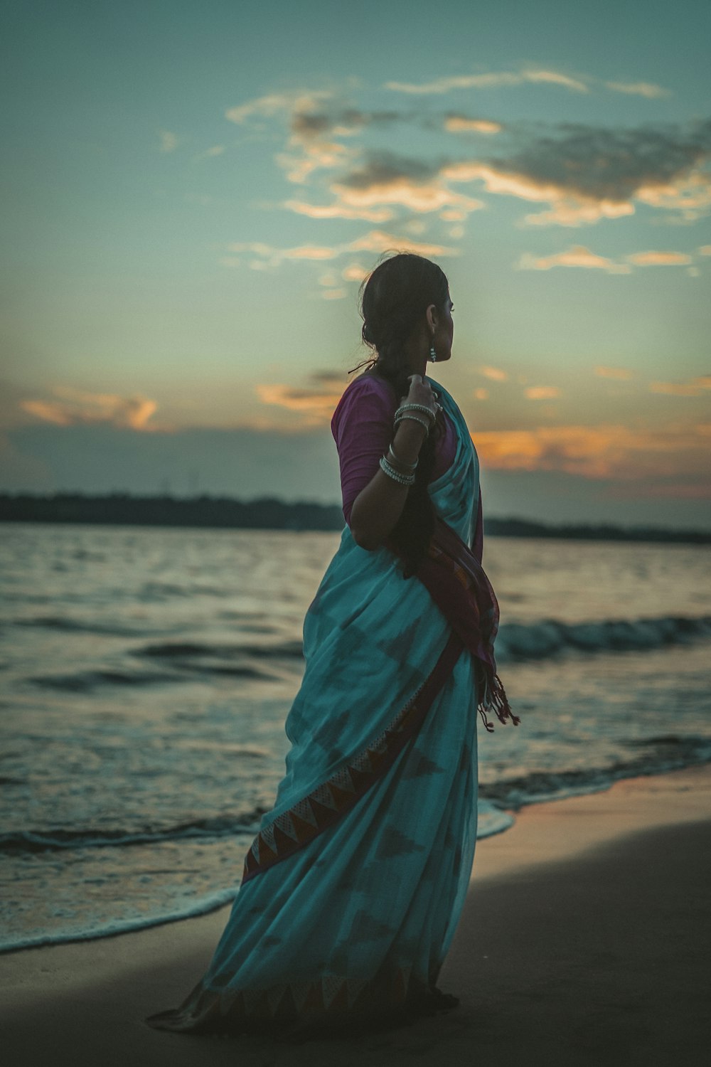 a woman standing on a beach at sunset