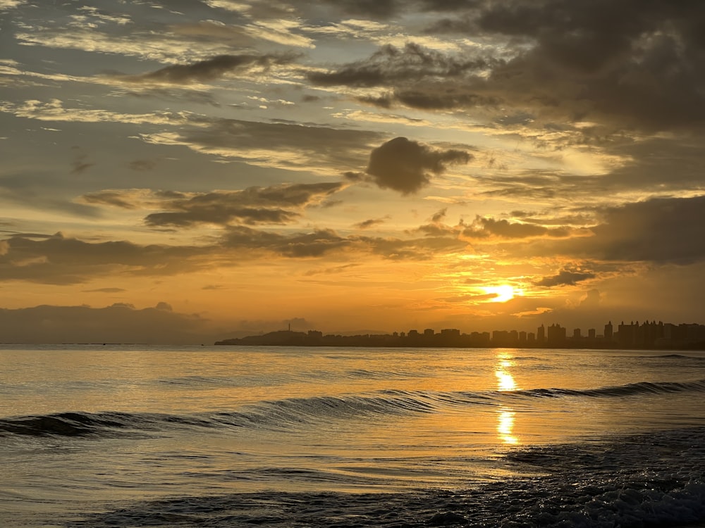 the sun is setting over the water at the beach