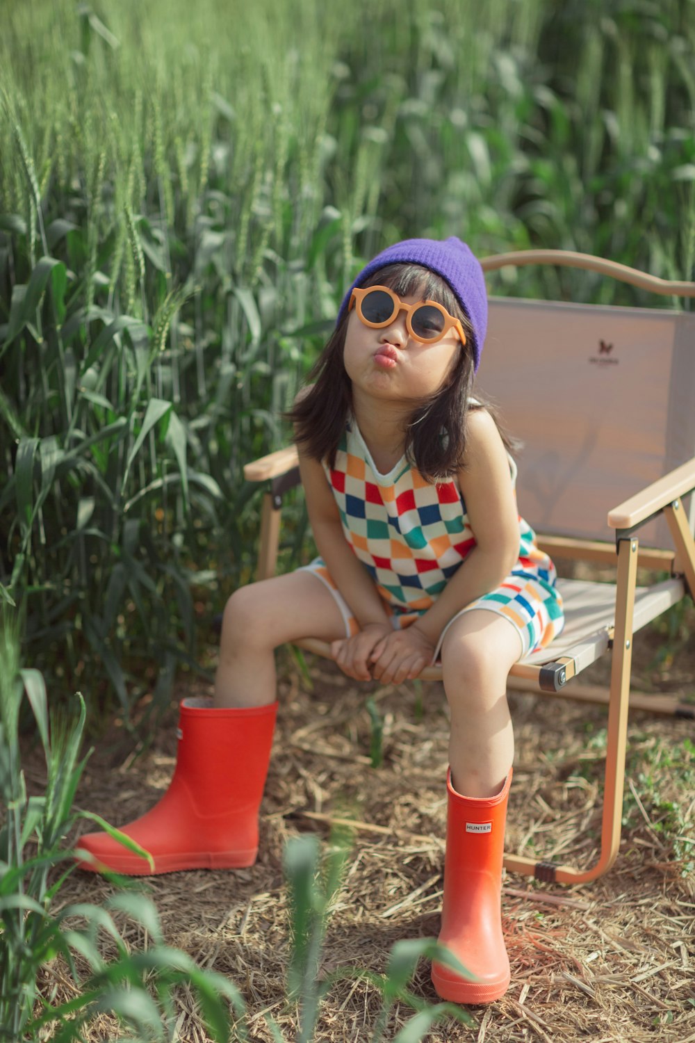 a little girl sitting on a chair in a field
