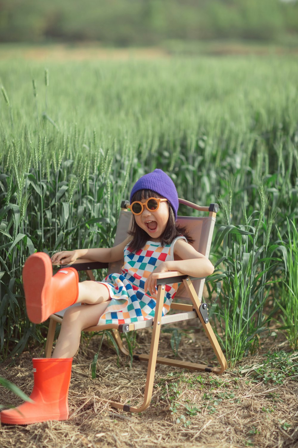 a little girl sitting in a chair in a field