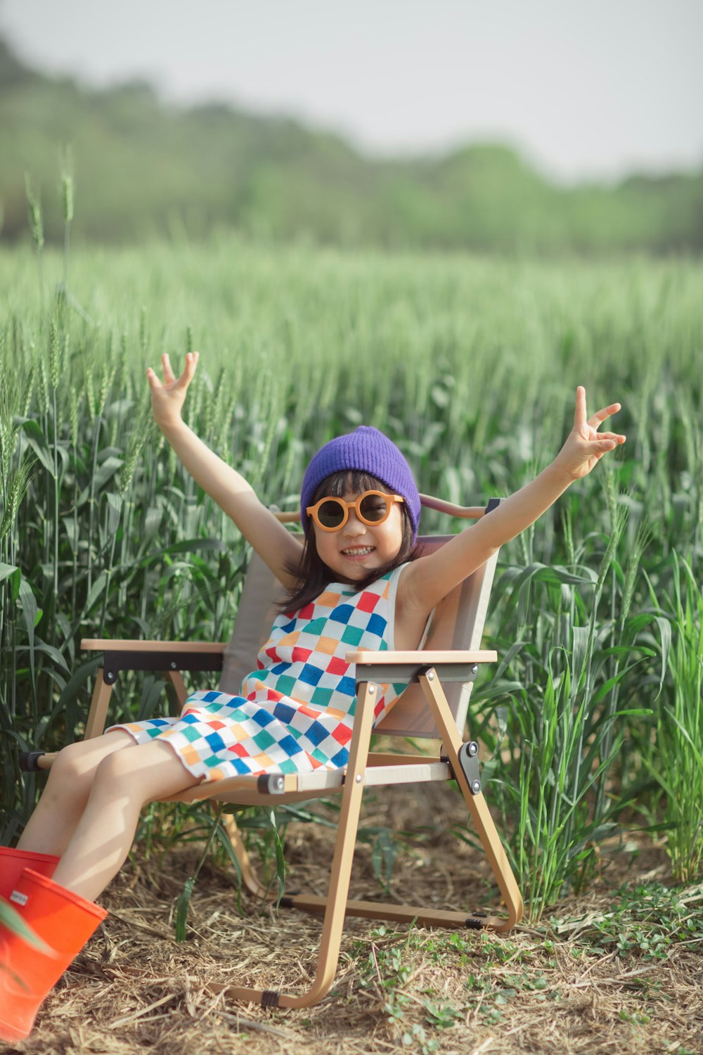 a little girl sitting in a chair in a field