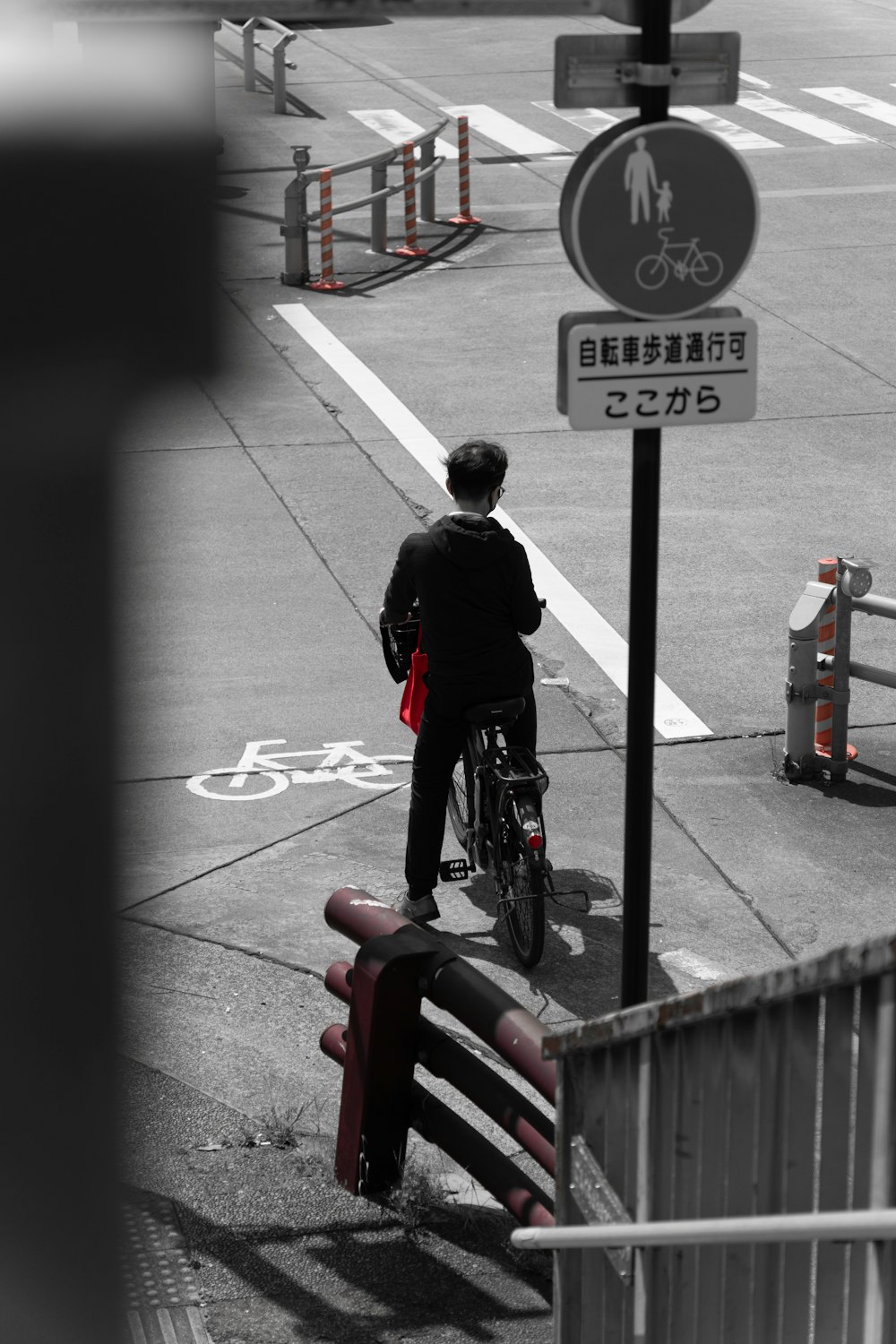 a man riding a bike down a street next to a street sign