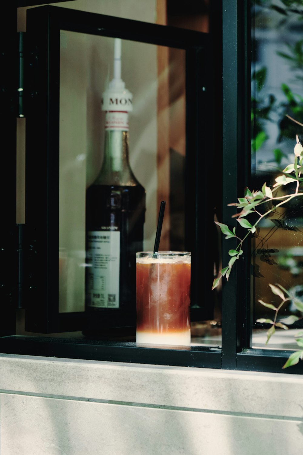 a bottle of alcohol and a glass on a window sill