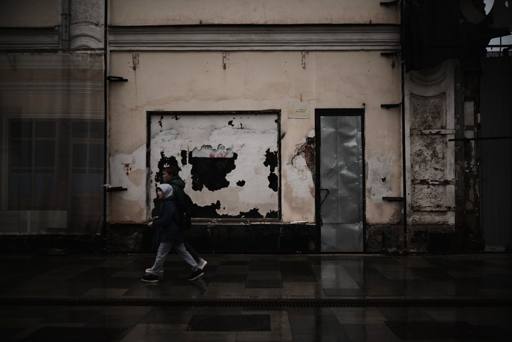 a man walking down a street next to a building