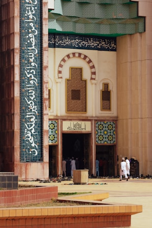 A welcoming entrance of Masjid As-Sahabah framed by Arabic-inspired patterns and greenery.