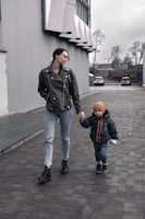 A mother and child wearing oversized denim jackets, walking through a golden maple leaf-lined street.