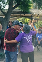 A group of friends laughing and holding award trophies at an outdoor celebration.