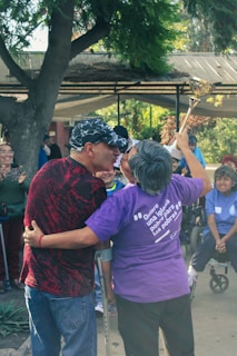 A group of friends laughing and holding award trophies at an outdoor celebration.